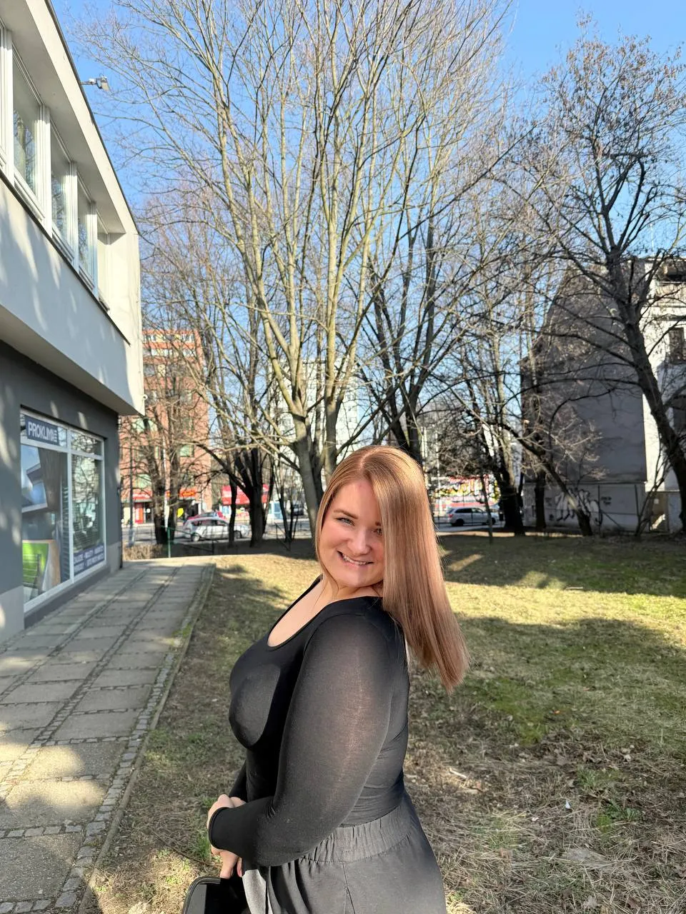 Blond vlasy na slunci, klientka se usmívá přes rameno — Newtone Brno