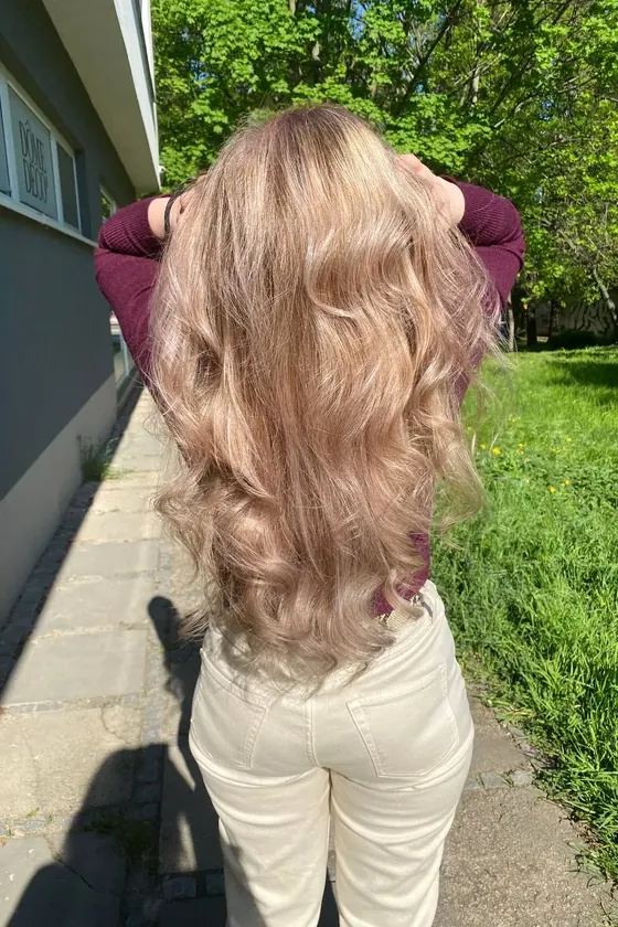 Dlouhé světlé vlasy ve volných vlnách kulmou, klientka zezadu venku — styling ze salonu Newtone Brno